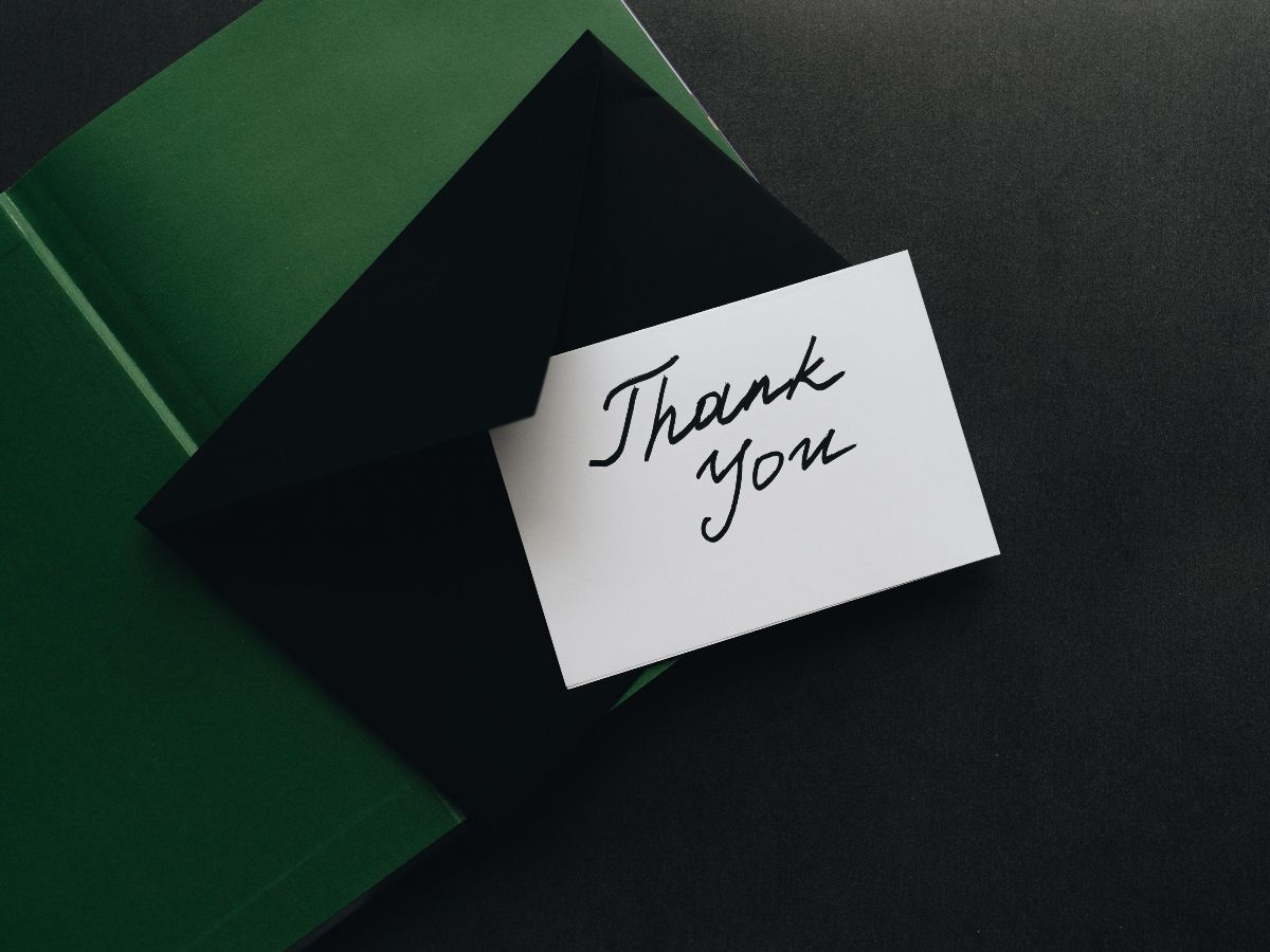 A picture of a white note with thank you in black font