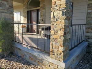 Contemporary VertiCable Series railings on a raised stone front porch of a home with stone columns.