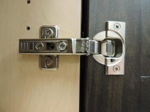 A silver hinge on a cabinet door