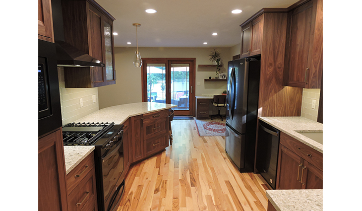 Remodeled kitchen with new dark wood cabinets and appliances with a curved bar side eating area