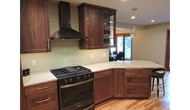 Newly renovated kitchen with wood cabinets and a black stove with hard wood floors
