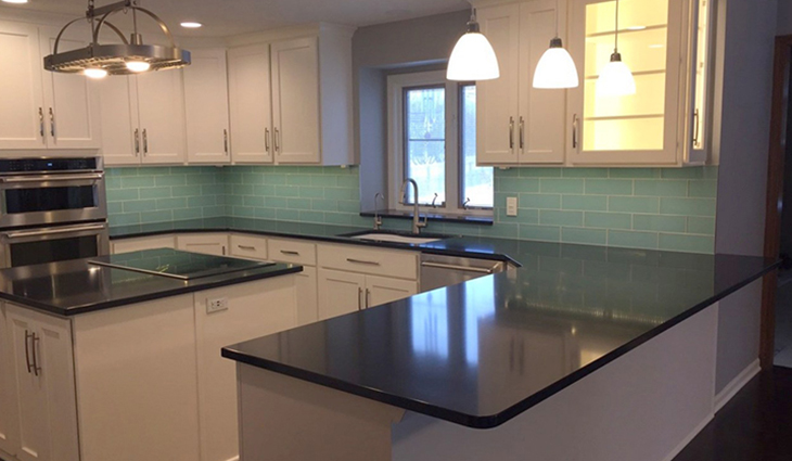 Kitchen with dark counters and teal backsplash
