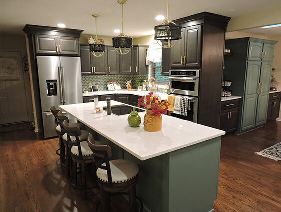 Kitchen remodel with dark gray cabinets, large island with stone countertop, wood floors, and pendant lighting.