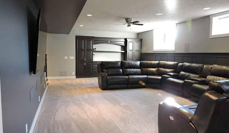 basement remodel with large black sectional couch