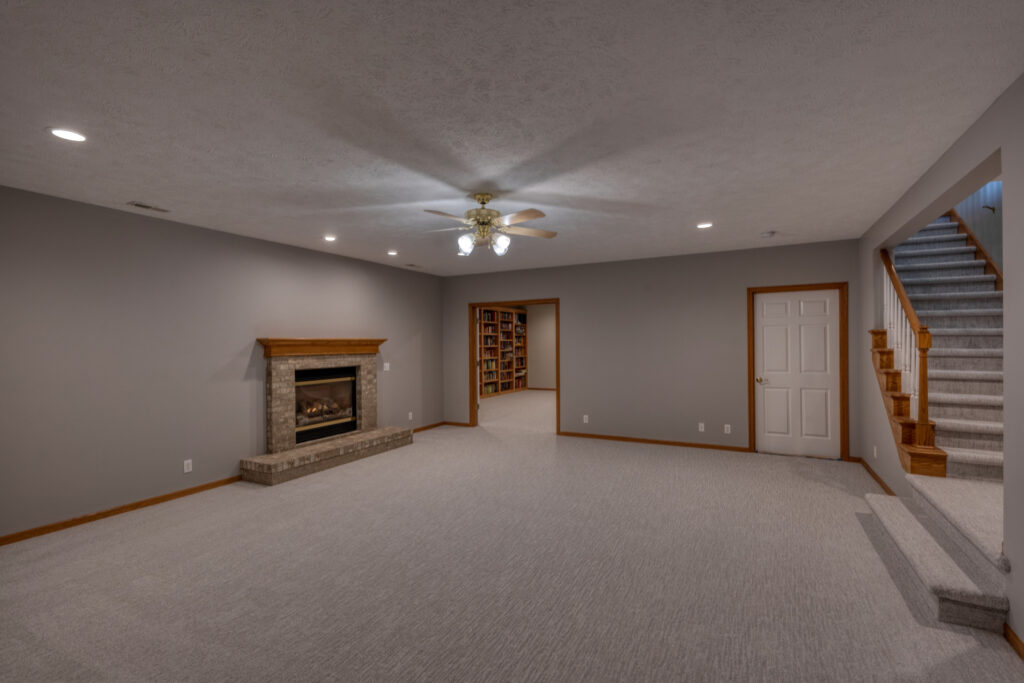 Basement remodel with light carpet, fireplace, and recessed lighting.