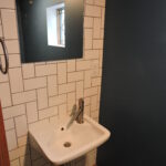 Remodeled small bathroom with modern white tile wall and modern faucet on pedestal sink.