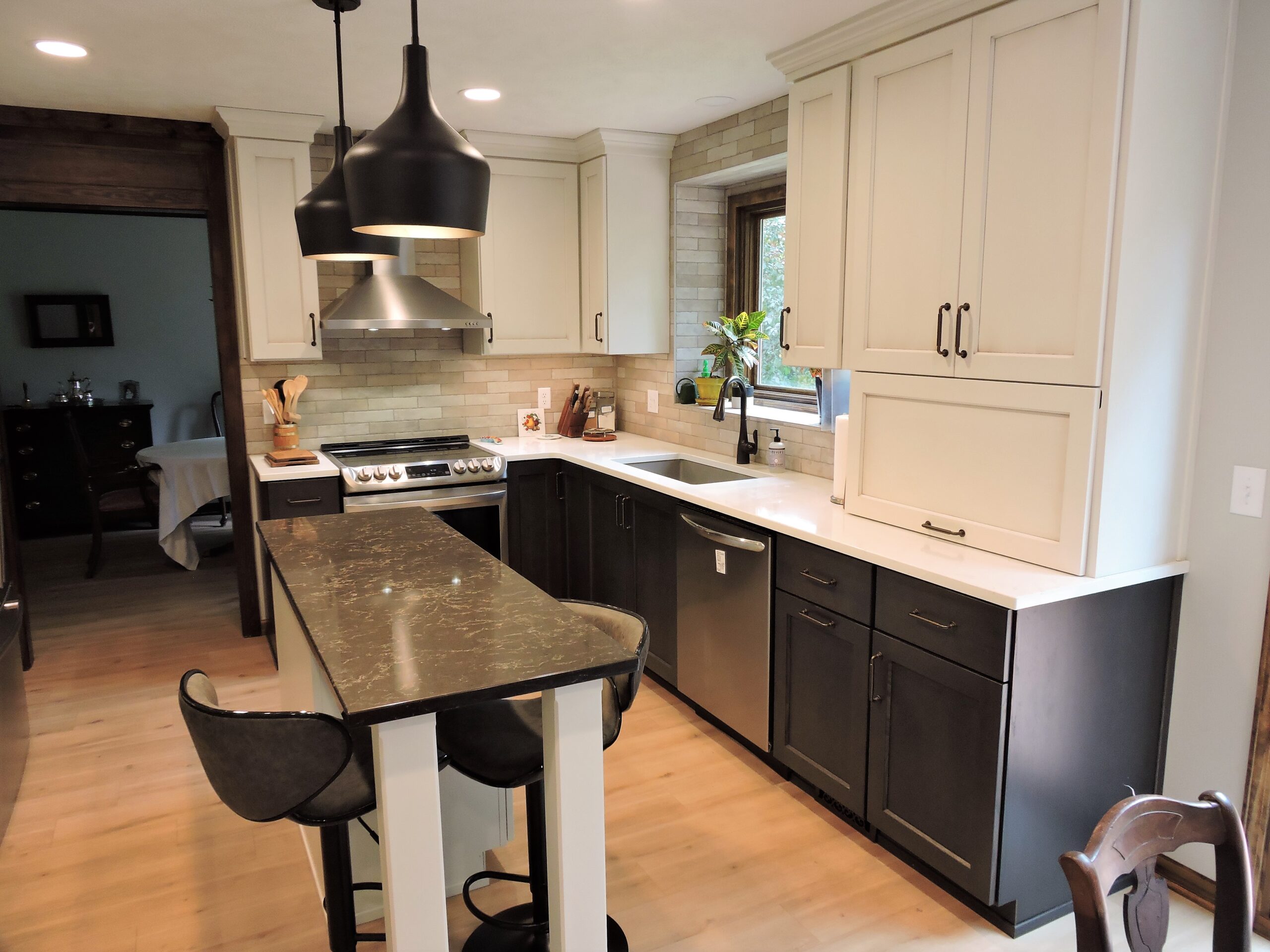 Kitchen with white cabinets and a dark marble island with two chairs