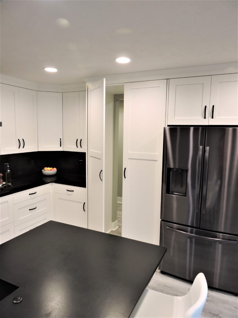 Kitchen with white cabinets and black counter tops, and recessed lighting.