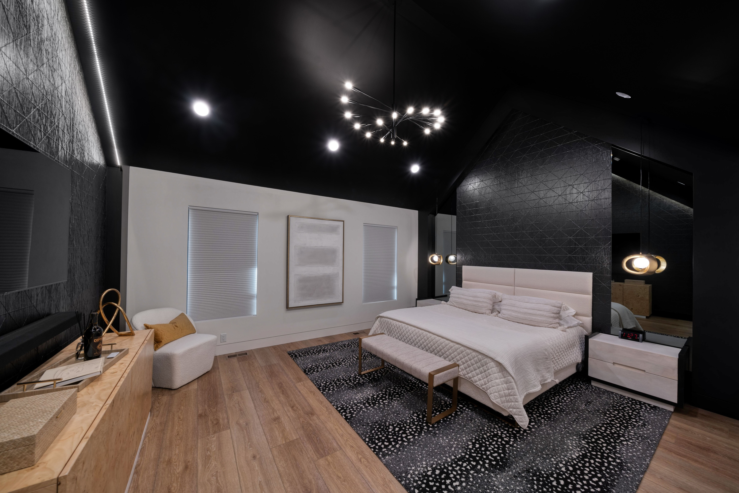 Modern bedroom with wooden floors, modern chandelier, and black walls and ceiling with recessed lighting