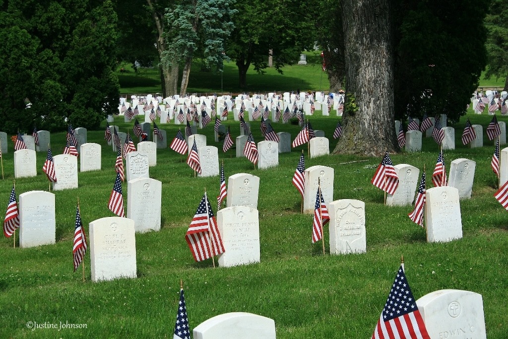 Cemetery with headstones, each with an American Flag