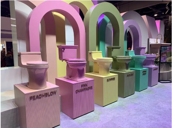 Kohler booth at KBIS 2023 held in Las Vegas. Row of different colored toilets, including peach, pink, yellow, and green.