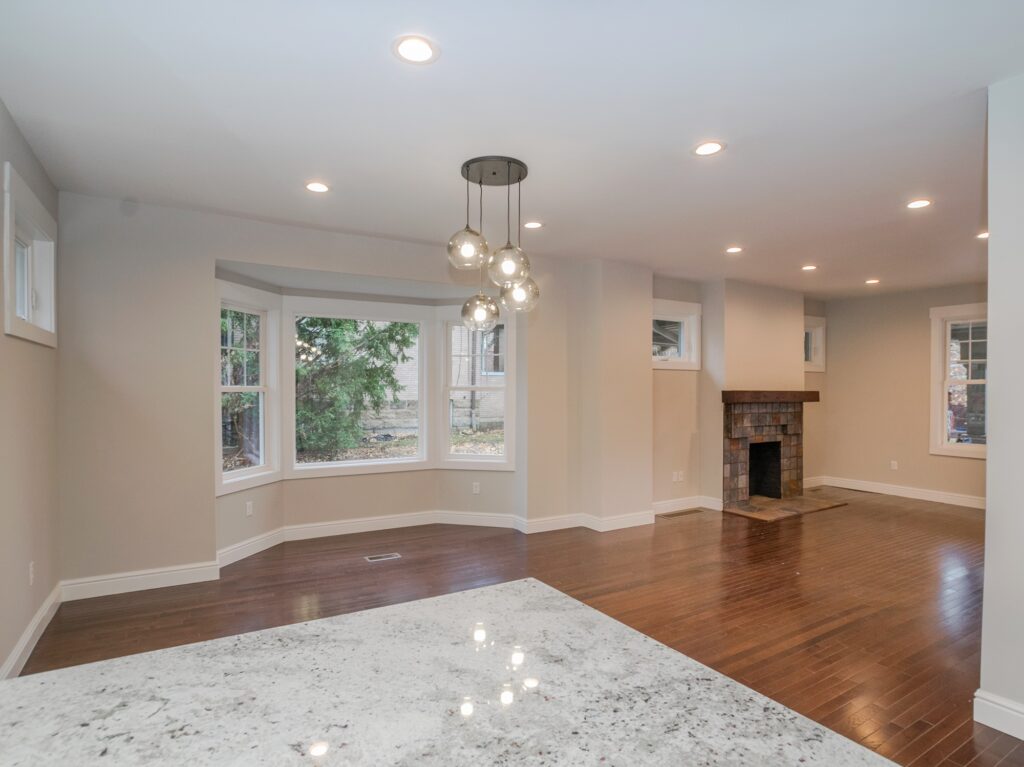 Living and dining room with wood floors, bay window, and a brick fireplace