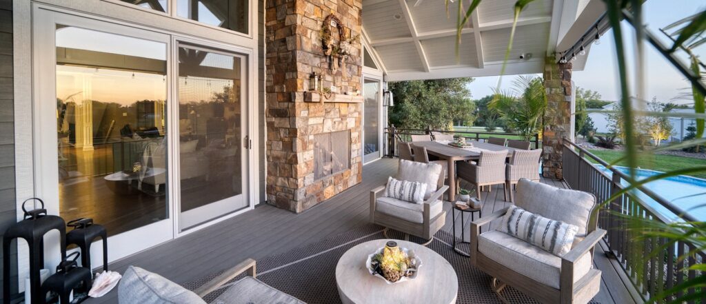 Deck addition overlooking the pool. Stone fireplace, light gray wood deck, cushioned patio furniture.