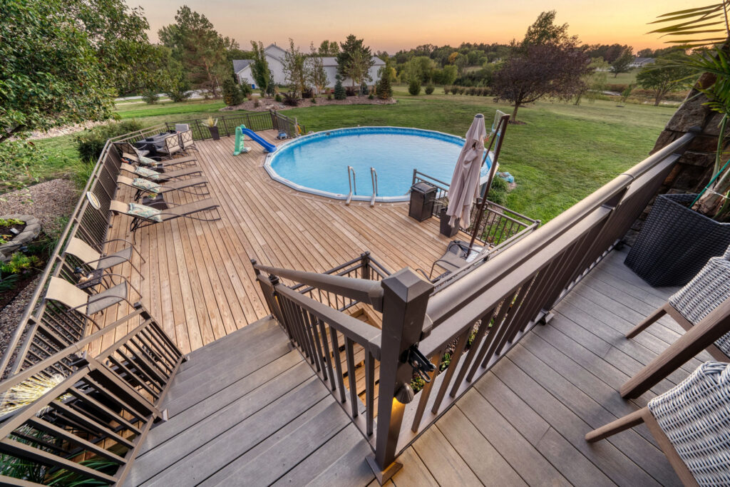 Two-story deck addition with pool view and large yard with trees in background