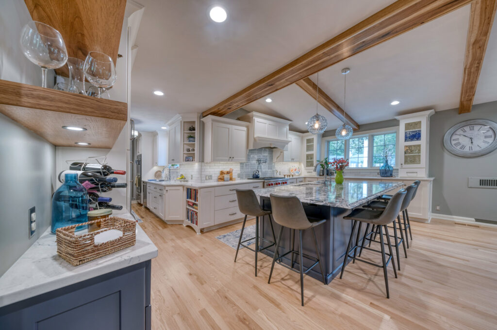 Renovated kitchen with white cabinets, gray stools, and wood flooring