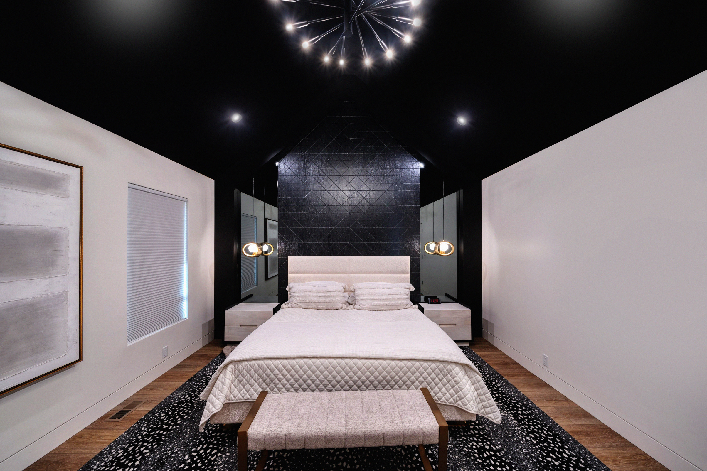 Remodeled modern bedroom with black ceiling & white walls with recessed lighting and chandelier.