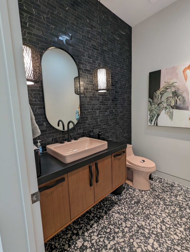 Updated bathroom from industry show in Vegas, with black tile wall and pink toilet and sink.