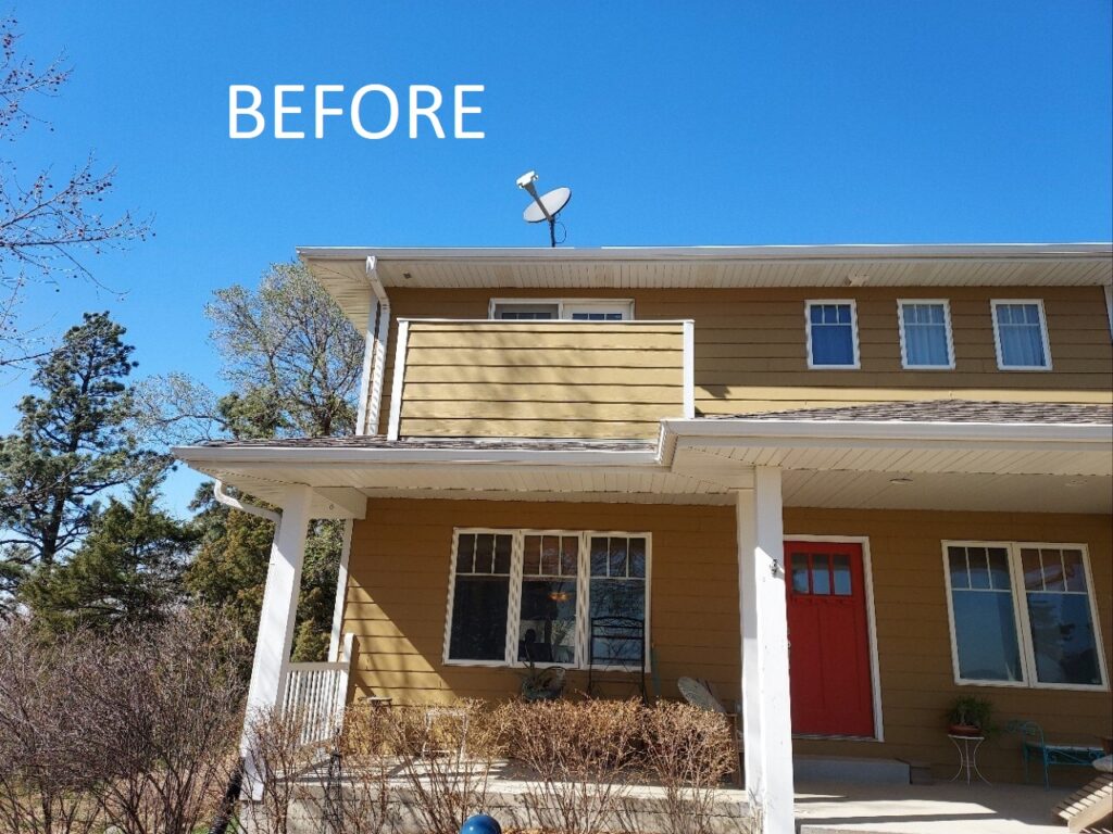 Before image from ground of a second-story balcony with solid wall matching home's tan siding.