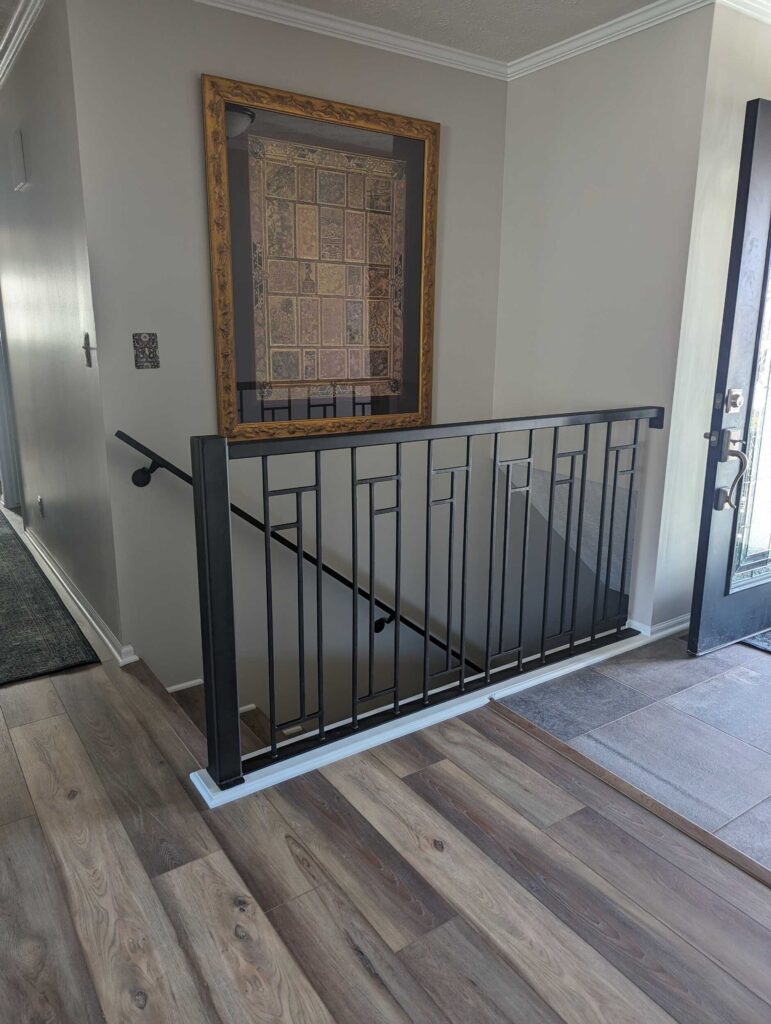 "After" image of modern-style black stair railing at the top of a staircase.