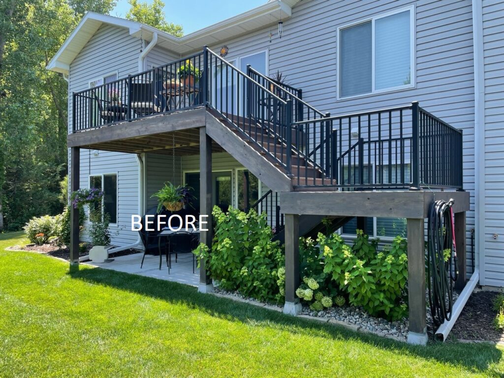 Before image of deck with staircase connecting to patio on back of two-story house.