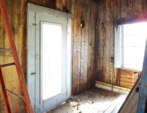 Inside of an old, run-down wooden room.