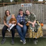 A family smiling with fall decorations around.