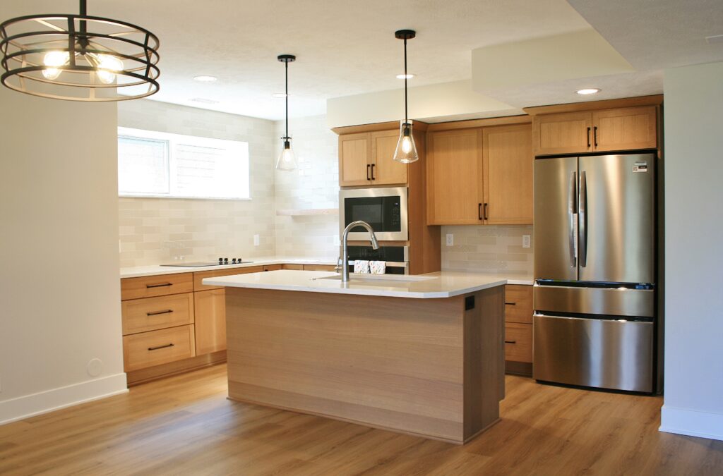 Vintage heights basement remodel. A kitchen with an island and pendant lights is seen.