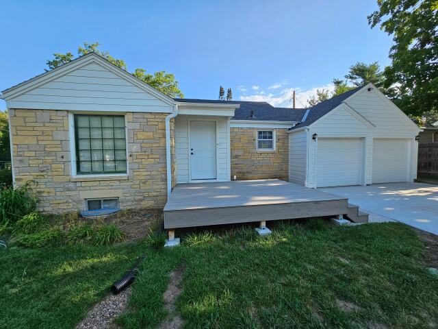 Exterior of modern home with gray/white siding and two white garage doors with brick surround.