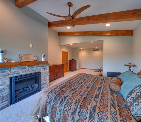 Home addition with large scenic windows, tan brick wall, and fireplace. Light wood floors and wood beam across ceiling.